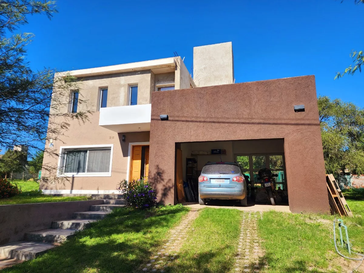 Casa en Barrio Tejas Cuatro, a 5 minutos de Villa Carlos Paz. Consta de 2 plantas: planta baja con living, cocina, comedor, baño completo y cochera para 2 vehículos; planta alta con 2 dormitorios (uno con balcón y baño en suite). 195 m² totales, 105 m² terminados y habitables, y 90 m² a terminar (50% avance de obra)
